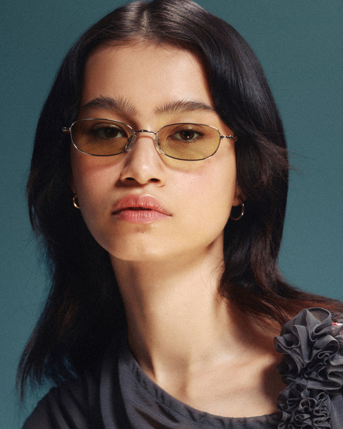 Quarter shot of Bonnie Clyde Tiptoe sunglasses in gold with green lenses.