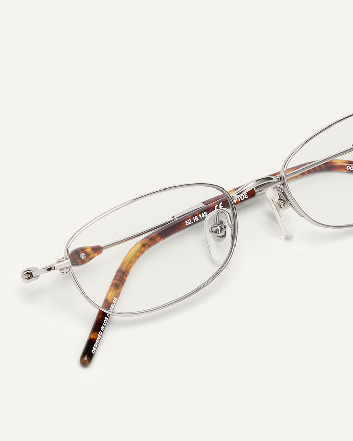 Close-up shot of Bonnie Clyde Tiptoe optical frames in silver with clear lenses.