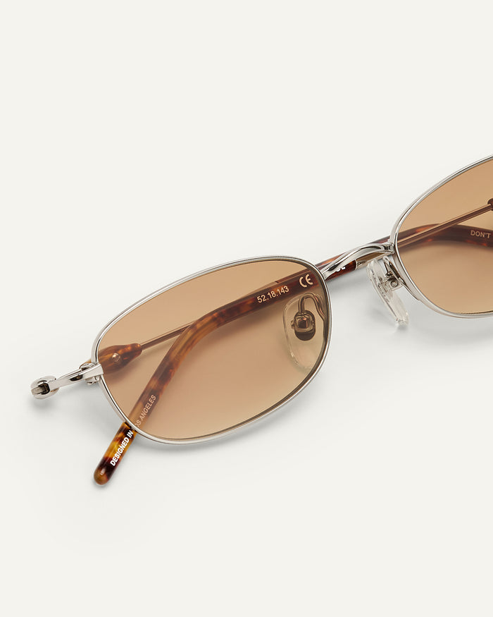 Close-up shot of Bonnie Clyde Tiptoe sunglasses in silver with brown lenses.