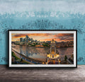 A framed photograph of the skyline of a city at sunset, with the city's iconic landmarks and buildings illuminated against a colorful sky.
