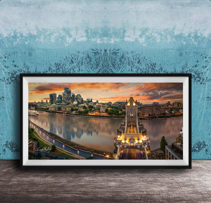 A framed photograph of the skyline of a city at sunset, with the city's iconic landmarks and buildings illuminated against a colorful sky.