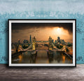A framed photograph of the Tower Bridge in London, England, with the city skyline and the River Thames in the background, illuminated by a warm, golden glow.