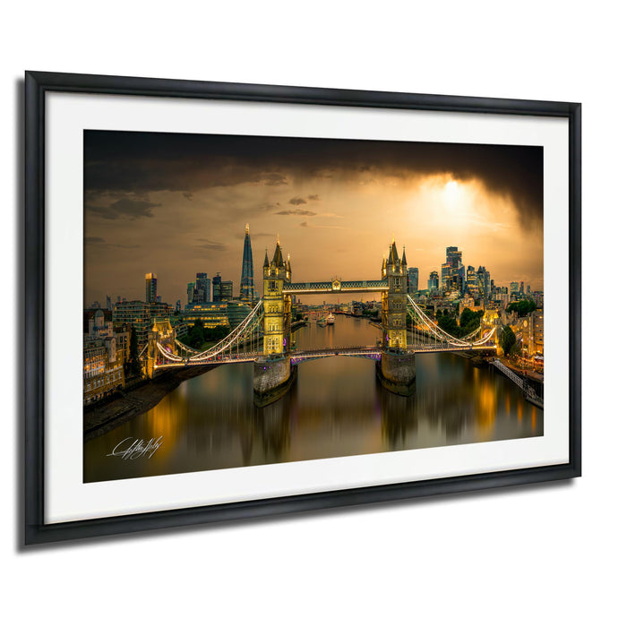 A framed photograph of the Tower Bridge in London, England, with the city skyline and the River Thames in the background, illuminated at night.