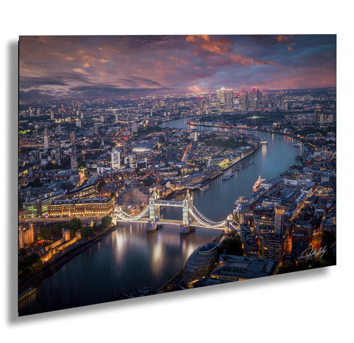 The image is a stunning aerial view of the city of London at night, showcasing the iconic Tower Bridge and the River Thames. The cityscape is illuminated by the glow of the lights, creating a vibrant and captivating scene.