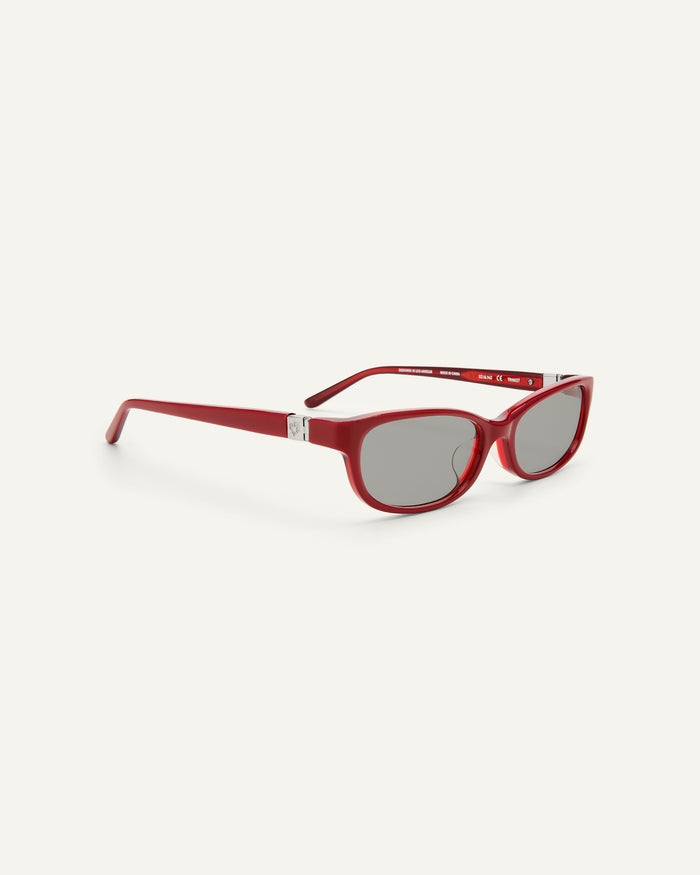 Quarter shot of Bonnie Clyde Trinket sunglasses in layered red with grey lenses.
