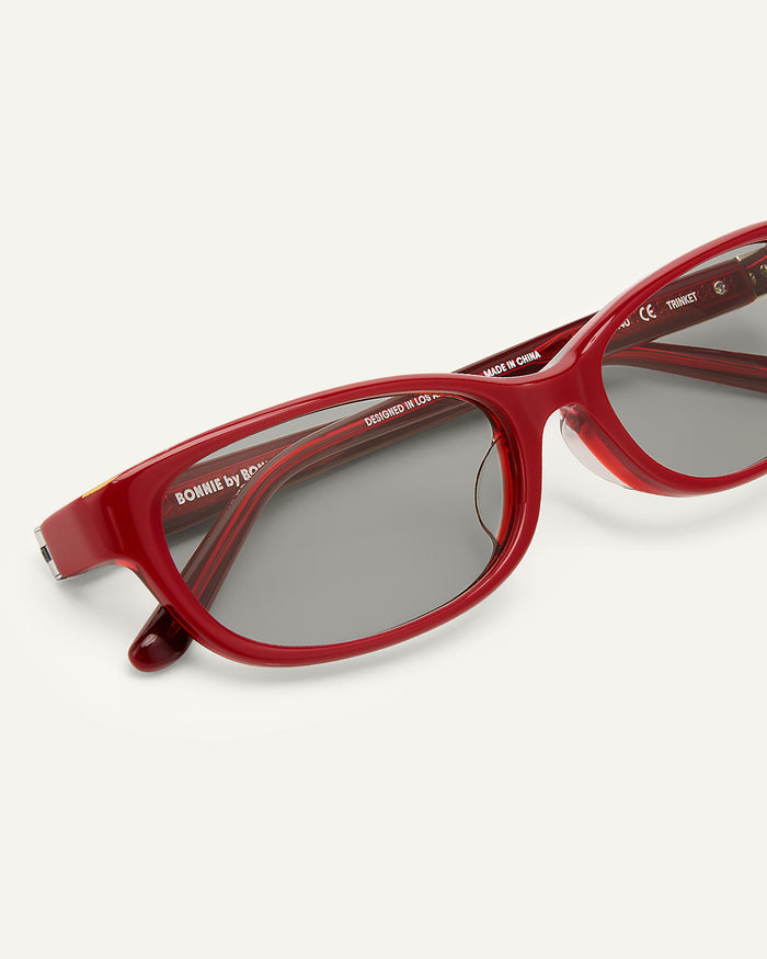 Side shot of Bonnie Clyde Trinket sunglasses in layered red with grey lenses.