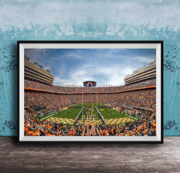 A framed photograph of a crowded football stadium during a game, with the field and stands filled with spectators.