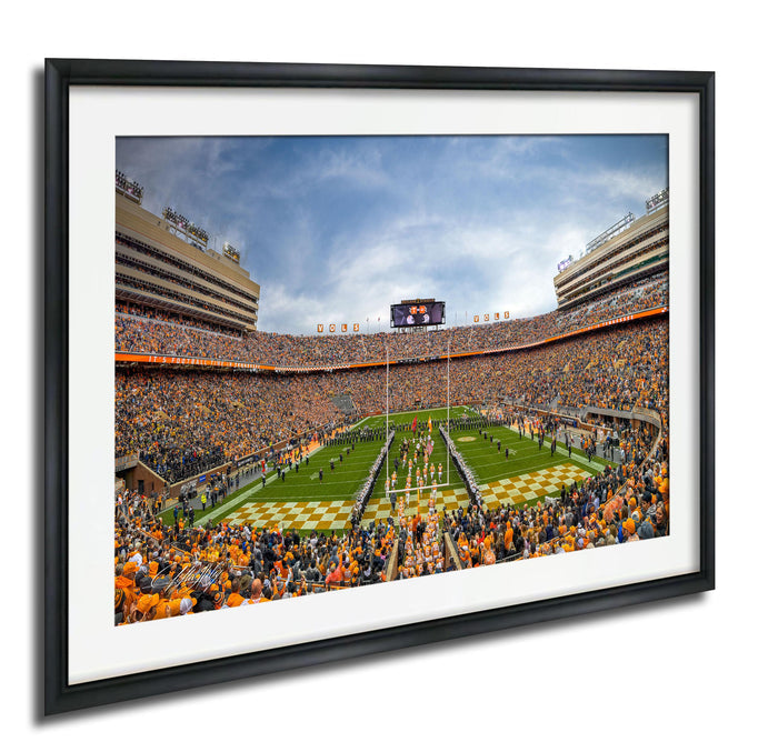 A framed photograph of a crowded football stadium during a game, with the field and stands filled with spectators.
