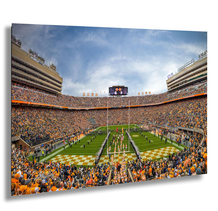A crowded football stadium with a large audience, featuring a football field, cheerleaders, and a large scoreboard.