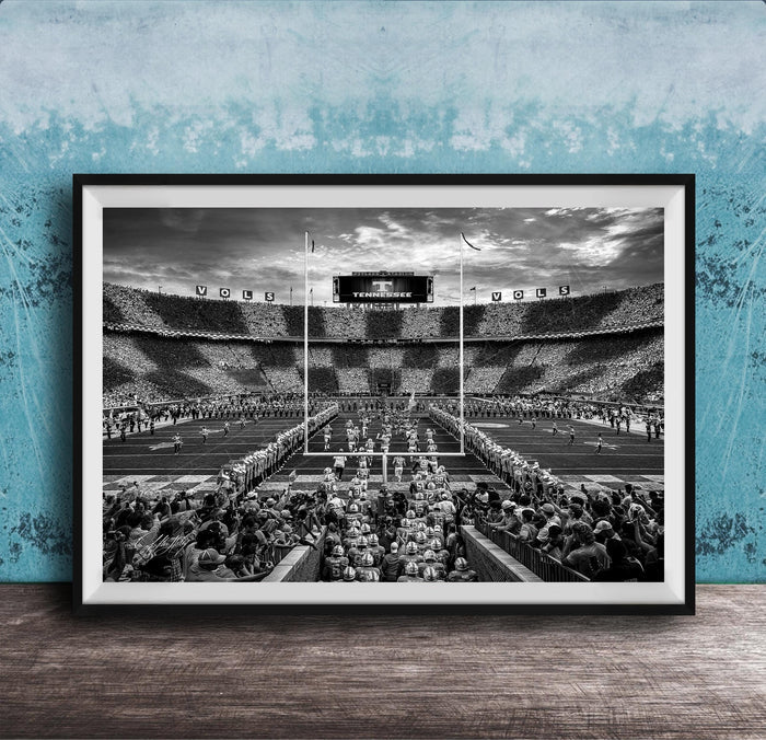 A black and white photograph of a crowded football stadium with a large audience, featuring a scoreboard and field markings.