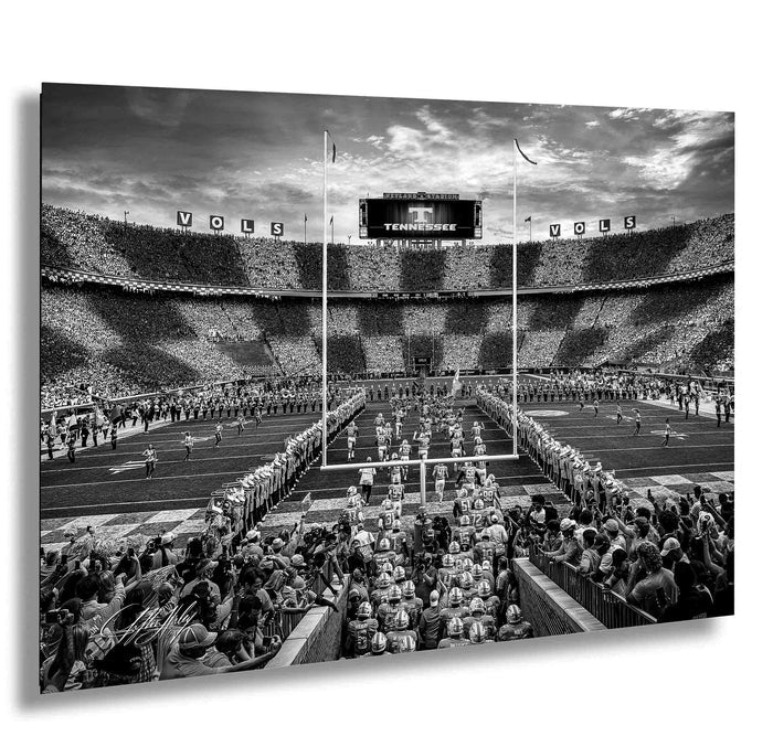 A black and white photograph of a football stadium during a game, with a large crowd of spectators filling the stands.