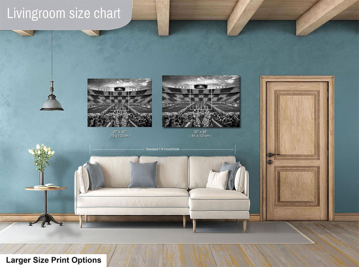 a living room with a white sofa, a wooden door, and a framed photograph of a stadium or arena. The living room appears to be designed for relaxation and comfort, with a focus on the seating area and the artwork on the wall.