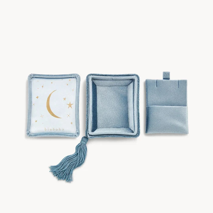 The velvet tassel box by bluboho features a light blue design and includes three pieces: an open box with a moon and stars motif on the inside lid, a deeper center box, and a smaller pouch with a flap closure on the right. The open box is accentuated with an elegant decorative tassel.