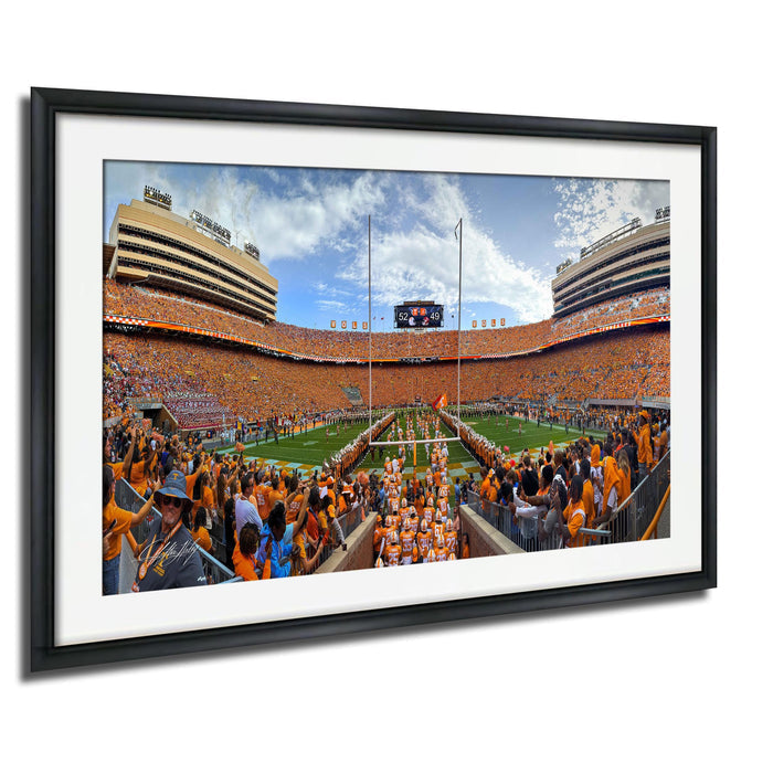 A framed photograph of a crowded football stadium during a game, with the stands filled with spectators and the field visible.