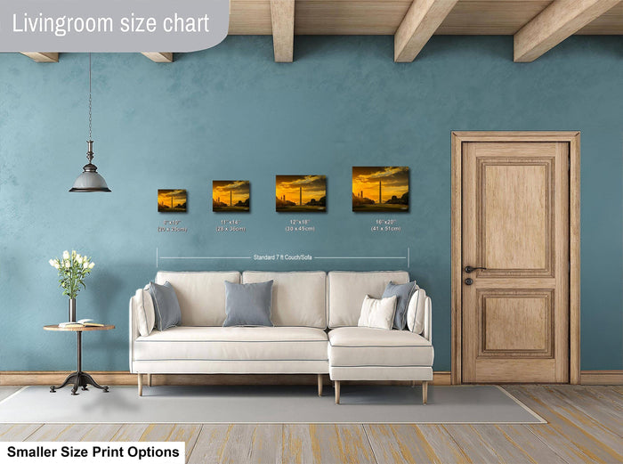 a living room with a white sofa, a wooden door, and a hanging light fixture. There are three framed artworks displayed on the wall, each with a different size and style. The living room appears to be designed for relaxation and comfort, with a focus on the artwork and the overall aesthetic.