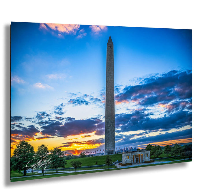 the Washington Monument, a tall obelisk, against a colorful sunset sky with clouds.