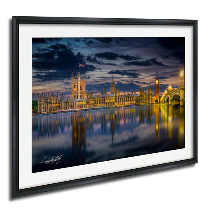 a cityscape at night, with a large building illuminated and reflected in the water below. The sky is dark, creating a dramatic atmosphere.