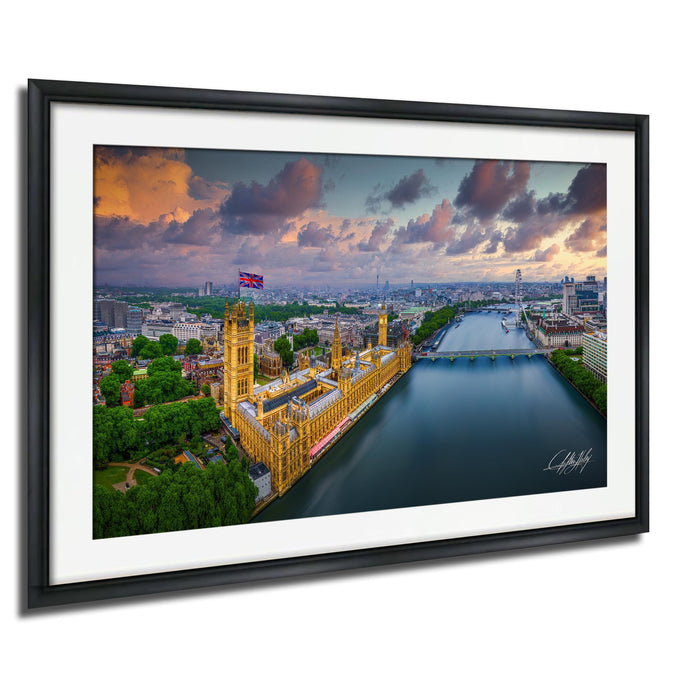 The image is a framed aerial view of the Palace of Westminster, also known as the Houses of Parliament, in London, England. The photograph is taken from a high vantage point, providing a panoramic view of the iconic building and its surroundings.