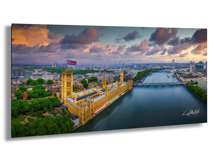 a cityscape with a large, ornate building with a distinctive yellow facade, situated along a river. The sky is filled with clouds, creating a dramatic backdrop for the scene. The city appears to be London, with the Houses of Parliament and other buildings visible in the background.