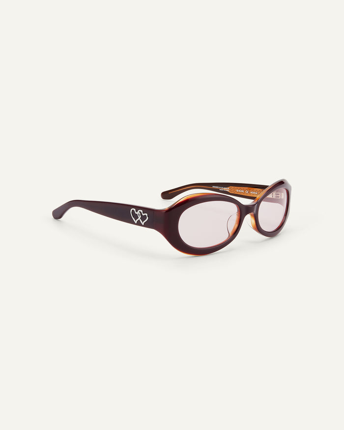 Quarter shot of Bonnie Clyde XOXOx2 sunglasses in dark pink with pink lenses.