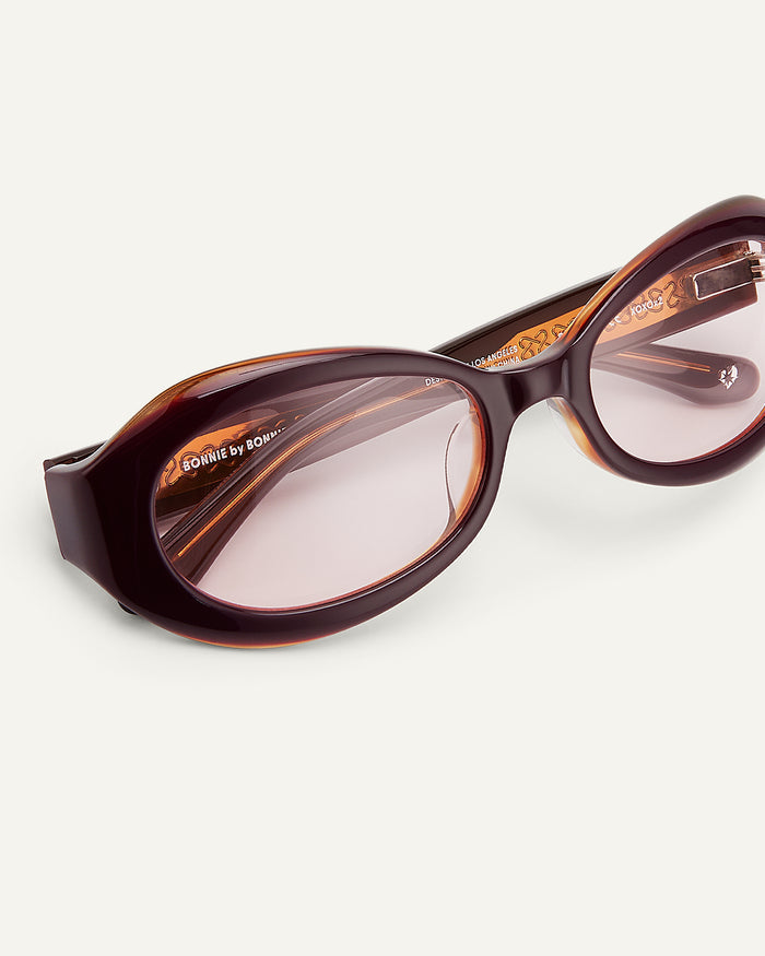 Side shot of Bonnie Clyde XOXOx2 sunglasses in dark pink with pink lenses.