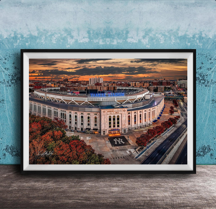 The image is a framed photograph of the Yankee Stadium in New York City, with a stunning sunset in the background.