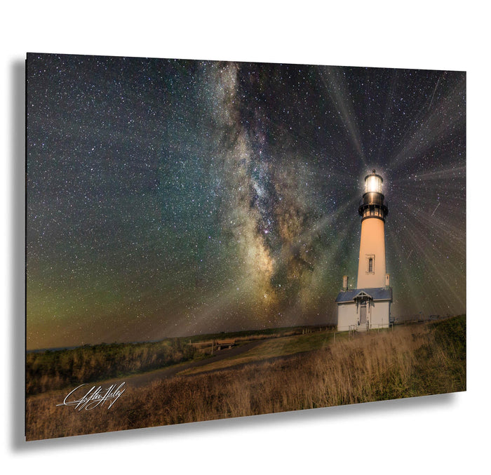 A lighthouse stands in a field under a starry night sky, with the Milky Way galaxy visible in the background.