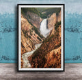 A framed photograph of a majestic waterfall cascading down a rugged, mountainous landscape.