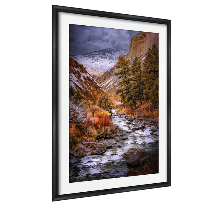 a serene mountain landscape with a winding river flowing through a valley, surrounded by snow-capped peaks and lush vegetation.