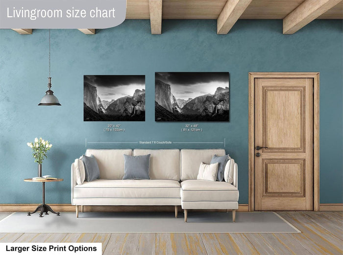 a living room with a white sofa, a wooden door, and two framed black and white landscape photographs hanging on the wall.