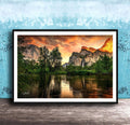 a serene landscape with a calm lake reflecting the vibrant colors of the sky, surrounded by lush greenery and towering mountains.