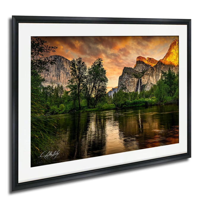 a serene landscape with a river reflecting the vibrant colors of the sky and surrounding mountains.