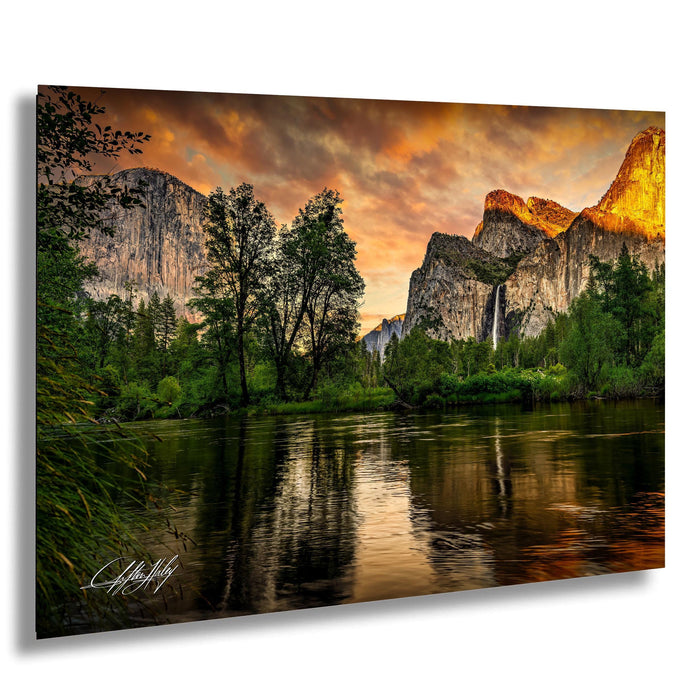 a serene landscape with a river reflecting the vibrant colors of the sky, surrounded by lush greenery and towering mountains.