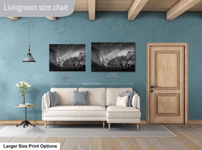 a living room with a white sofa, a wooden door, and two framed black and white landscape photographs hanging on the wall.